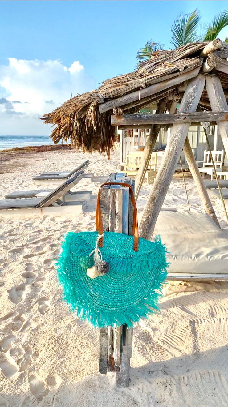 Azure raffia beach bag on sandy beach near cabana, 